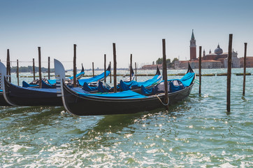 Fototapeta na wymiar Gondolas docked to the poles on Canal in Venice