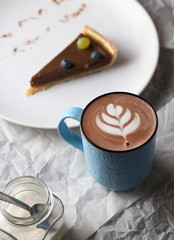 Cup of cacao and a piece of cake. Latte art.