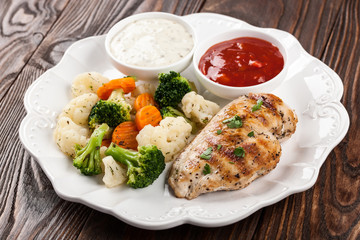 Grilled chicken breast fillet with stew vegetables and sauces