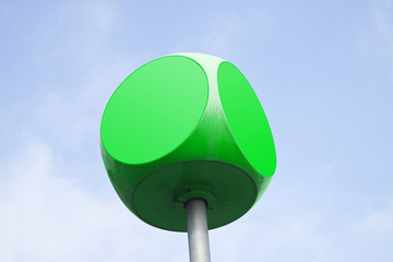 Green  cube with rounded edges against sky background with copy space
