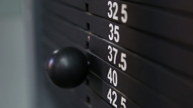 The athlete changes the weight of the load on the trainer in the gym
