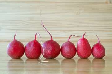 Red radishes arrayed on wooden table.