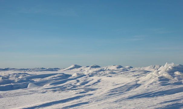 Snow desert and blue winter sky. Mountains on the horizon
