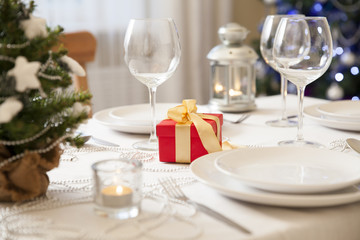 Beautiful christmas table served and decorated with candles. Christmas tree with lights on the background