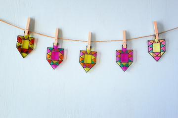 image of jewish holiday Hanukkah with Stained-glass colorful dreidels (spinning top) hanging on a rope over wooden background   © tomertu