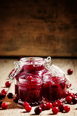 Delicious cranberry jam in glass jars and fresh cranberry on an