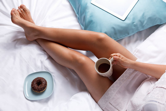 Woman eating a donut in the bed