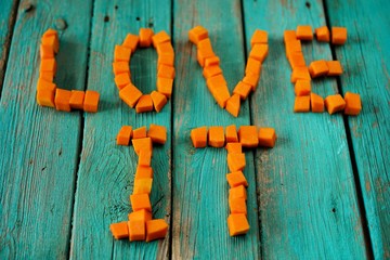 Words Love It written by fresh bright orange pumpkin cubes on wo