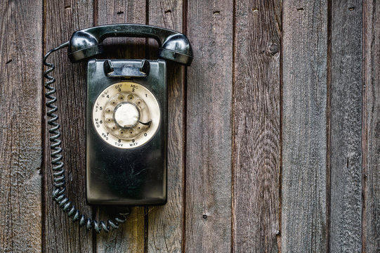 Retro rotary black phone on a wooden wall