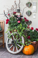 Fototapeta na wymiar Halloween decoration - pumpkin, Scarecrow, old wooden wheel near the door of the house