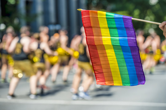 Rainbow flag floating in front of blurred gay dancers