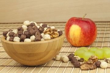 Chocolate cereal balls in a bowl of bamboo. Healthy breakfast with fruit and milk. A diet full of energy and fiber for athletes. Quick to prepare homemade breakfast.
