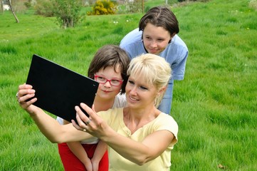 Fototapeta premium Family sitting on the lawn and using digital tablet