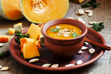 Pumpkin soup with oil and seeds in a clay bowl in a rustic style