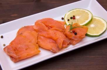 Smoked salmon on tray on wooden table seen close
