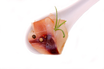 Smoked swordfish on teaspoon on white background seen from above and close