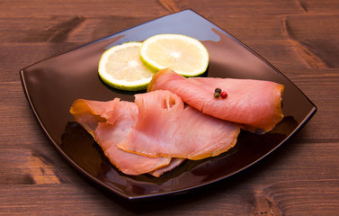 Smoked tuna on black plate on wooden table
