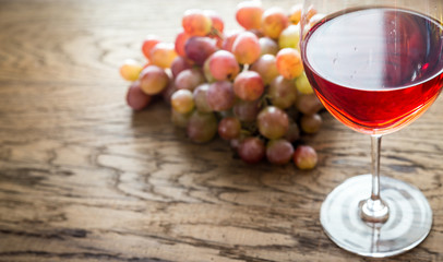 Glass of rose wine with bunch of grape