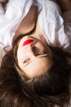 Upside down image of young woman with red lips laying