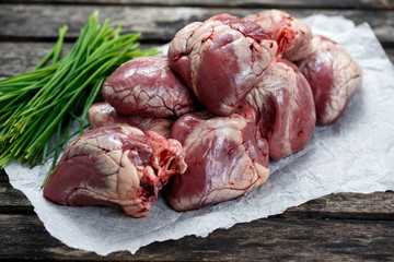 Raw Lamb Hearts on crumpled paper, decorated with vegetables. on old  wooden table