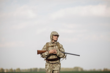hunter in camouflage clothes ready to hunt with hunting rifle