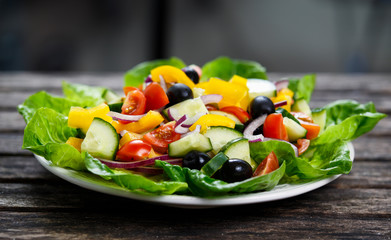 Fresh Vegetable  Salad with, black olives, cherry tomatoes, yellow pepper, red onion, cucumber. On wooden table.