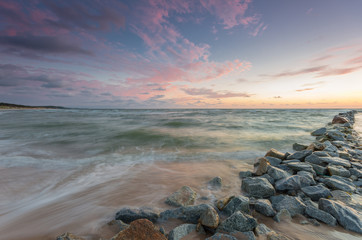 Baltic sea coast at sunset, with granite groyne in Rowy, near Ustka, Poland