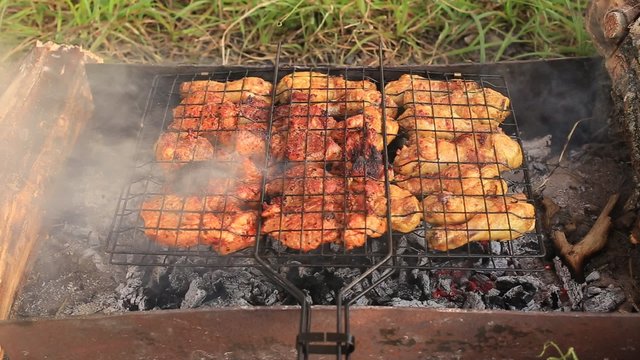 
On hot coals is grill with meat. There is a strong smoke and burning embers
