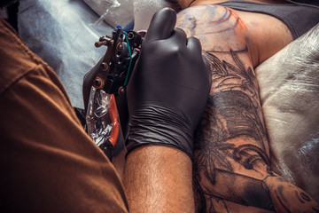 Professional tattoo artist working tattooing in studio
