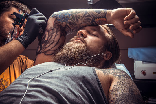 Tattooist doing tattoo in tattoo studio