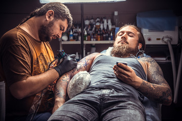 Fototapeta premium Professional tattoo artist makes cool tattoo in tattoo parlor