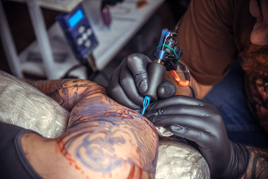 Tattoo specialist makes tattoo pictures in tattoo parlor