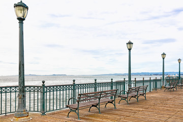 San Francisco Bay wooden pier with benches and light posts. Copy space
