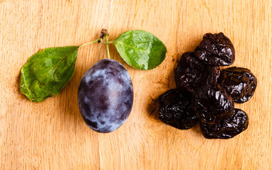 dried plums and fresh prune fruit on wooden table