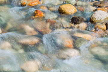 Pebble stones in the river water close up view blurred motion