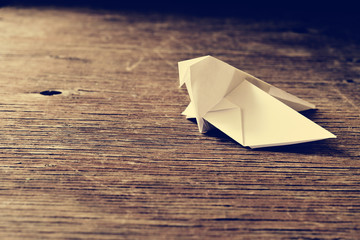 Fototapeta na wymiar origami bird on a wooden surface, retro effect