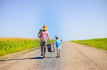Obraz premium Family walking with old suitcase on sunny summer countryside