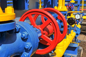 Red faucet with steel pipe in natural gas treatment plant in bright sunny summer day