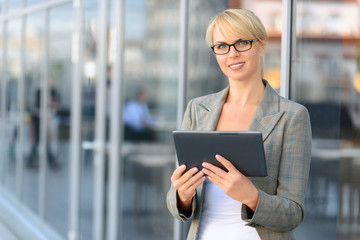 Pleasant businesswoman standing near office building