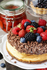 Cheesecake with chocolate topping decorated with summer fruits