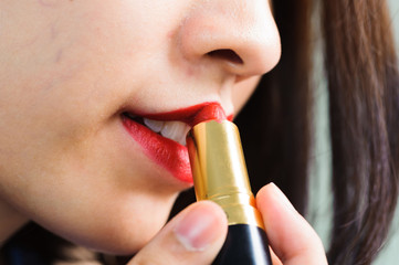 Young woman apply red lipstick