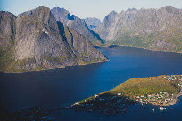 Fototapeta na wymiar Beautiful norwegian landscape with famous top peak Reinbringen, Lofoten Islands, with a group of hikers tourists, and with a view on famous fishing village Reine, Moskenesoya and norwegian sea 