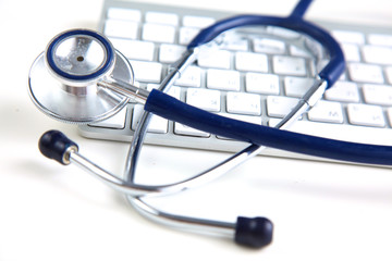 A medical stethoscope near a laptop on a wooden table, on white