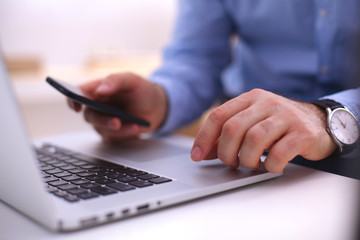 Fototapeta premium Businessman at a table with a smartphone and a laptop
