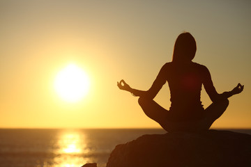 Woman meditating and practicing yoga watching the sun