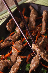 Cooking Bulgogi beef with carrot on the grill macro. Vertical
