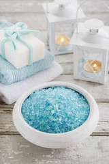 Fototapeta na wymiar Bowl of blue sea salt, two towels and bar of handmade soap on wooden table