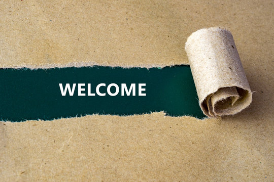 Torn brown paper on green surface with "WELCOME" word.