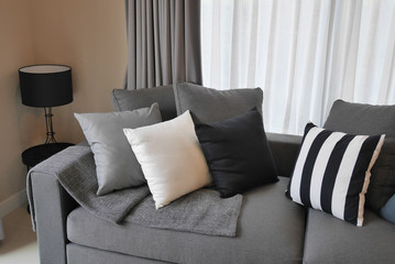stylish living room design with grey and black striped pillows on comfortable sofa