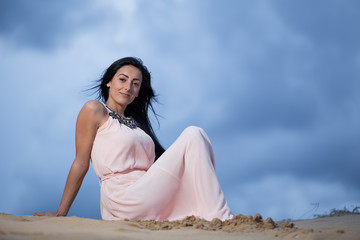 Fototapeta na wymiar Beautiful woman sitting alone on a sand dune